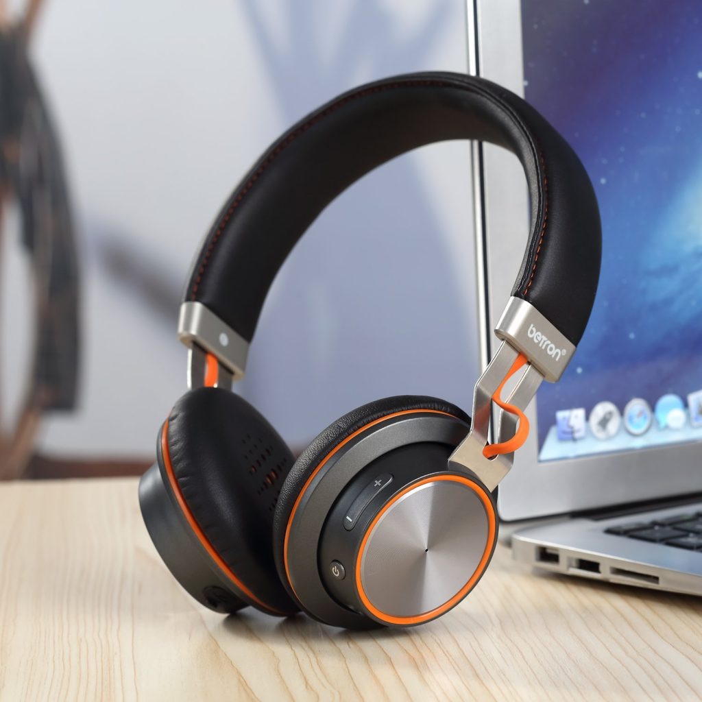 Stock image of the Betron S2 Headphones next to a laptop.