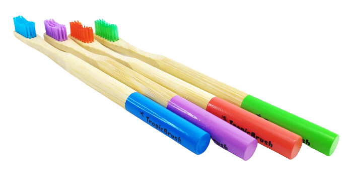 TropicBrush Bamboo Toothbrushes. Image shows 4 toothbrushes lined up. There's a blue, purple, red and green toothbrush.