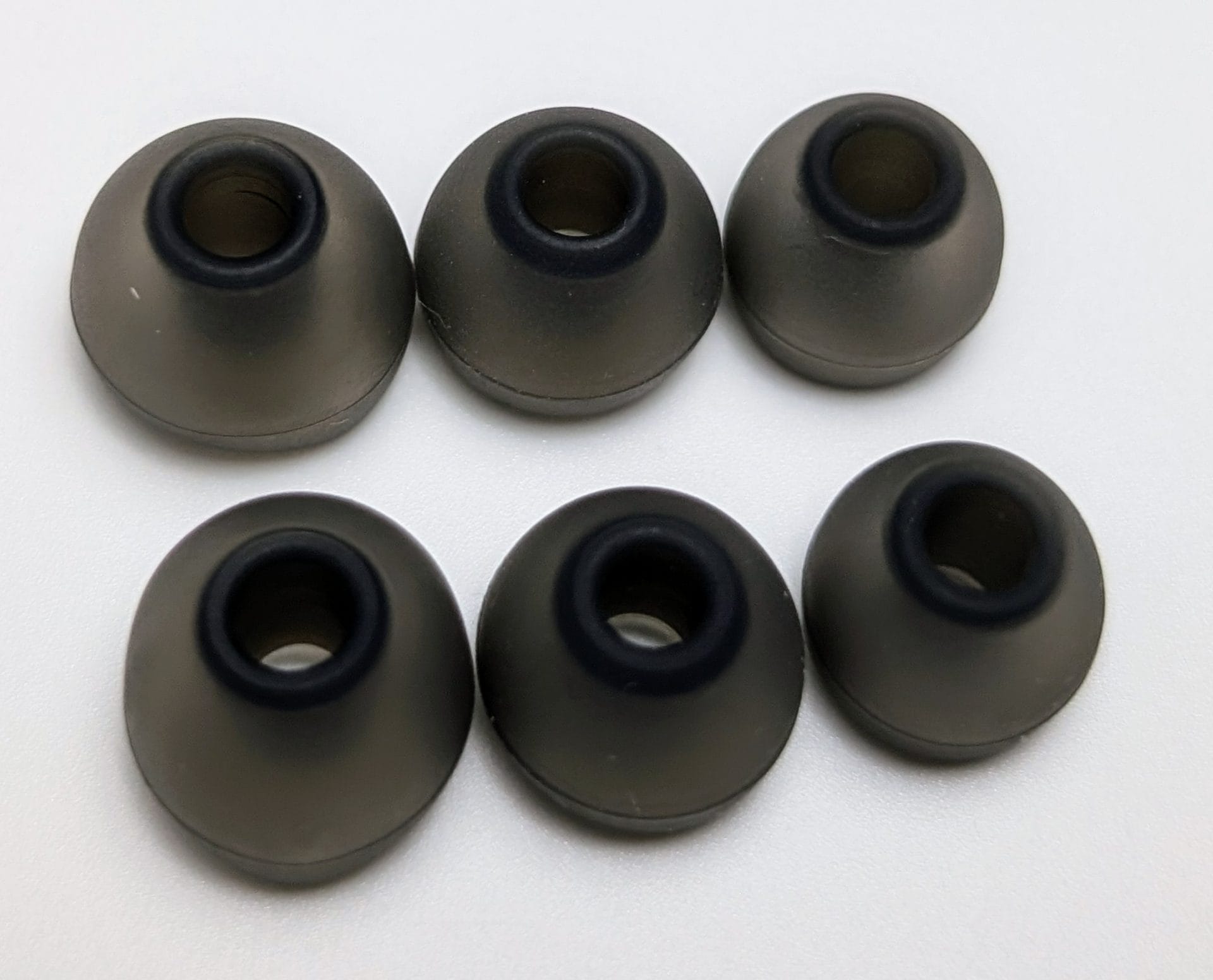 TKZK TK02 IEMs Image of six black foam ear tips for earbuds, arranged in two rows of three on a white background. Each ear tip has a cylindrical shape with a hollow center, designed to fit over earbud speakers for a comfortable fit in the ear canal