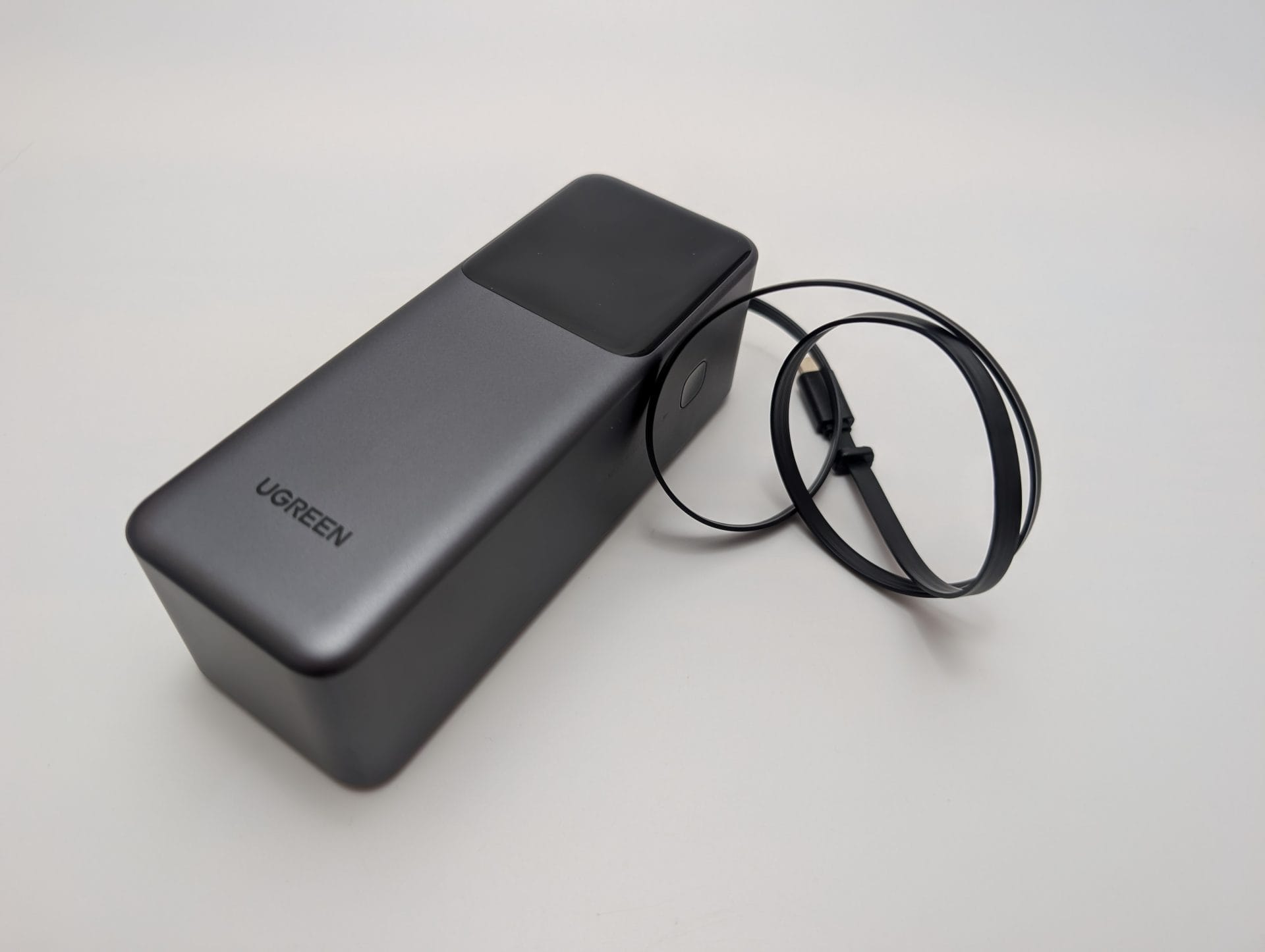 UGREEN Nexode Power Bank 20000mAh 165W with Retractable USB-C Cable UGREEN Nexode 20000mAh 165W Power Bank with Retractable USB-C Cable. The image shows a sleek, silver and black power bank with a glossy top panel and the UGREEN logo. A retractable black USB-C cable is extended from the device, coiled neatly beside it, on a white background.