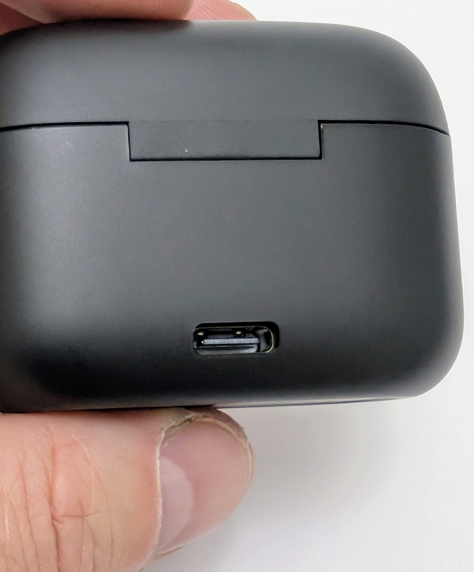 TOZO T20 Wireless Earbuds Image of a hand holding a closed black TOZO T20 wireless earbuds charging case, showing the USB-C charging port on the back against a white background.