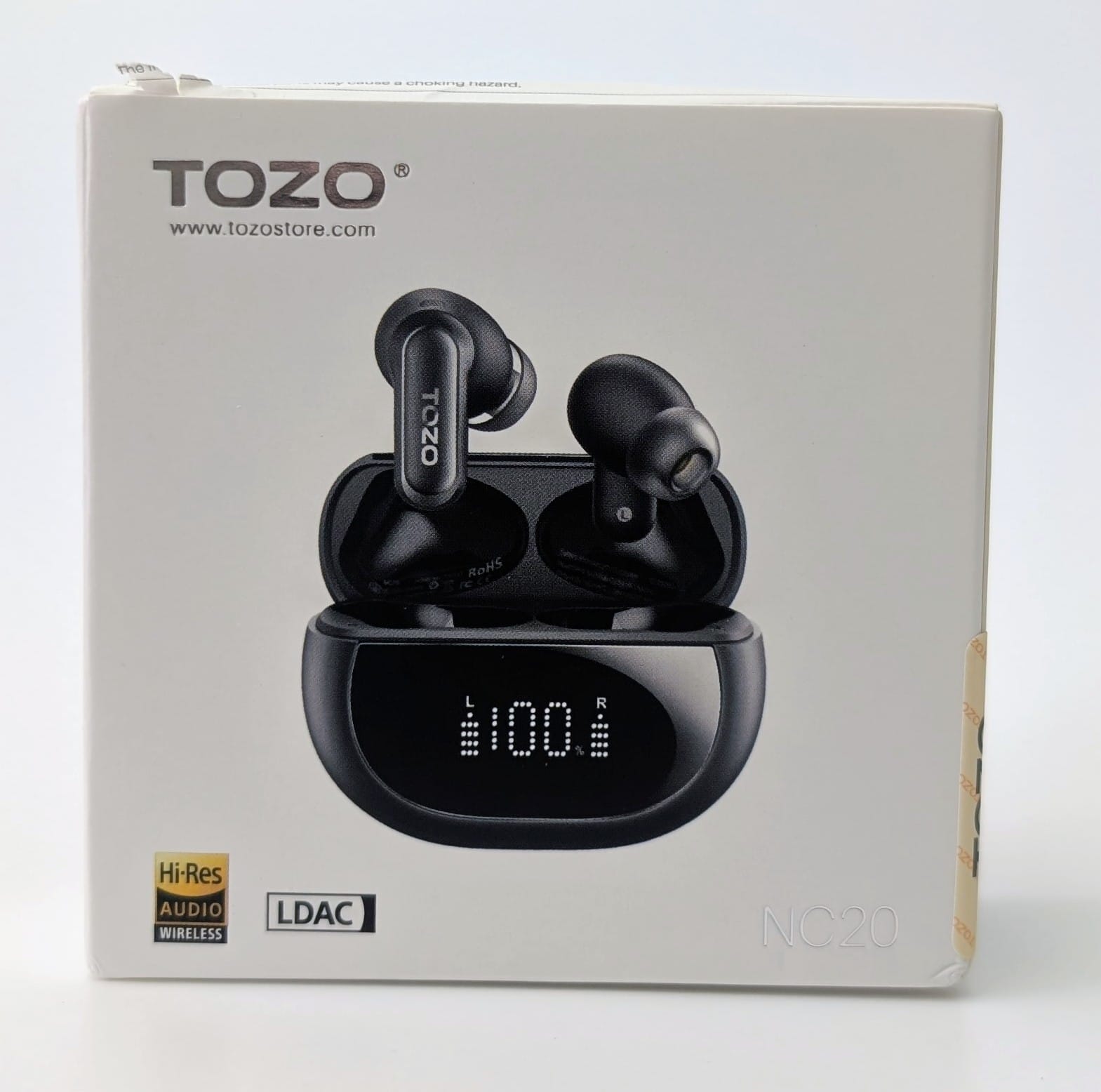 TOZO NC20 Earbuds White retail box for TOZO NC20 wireless earbuds, featuring an image of the open black charging case with both earbuds inside. The case's digital display shows 'L 100% R' indicating full battery. Visible branding includes TOZO logo, Hi-Res Audio Wireless, LDAC, and model name NC20."