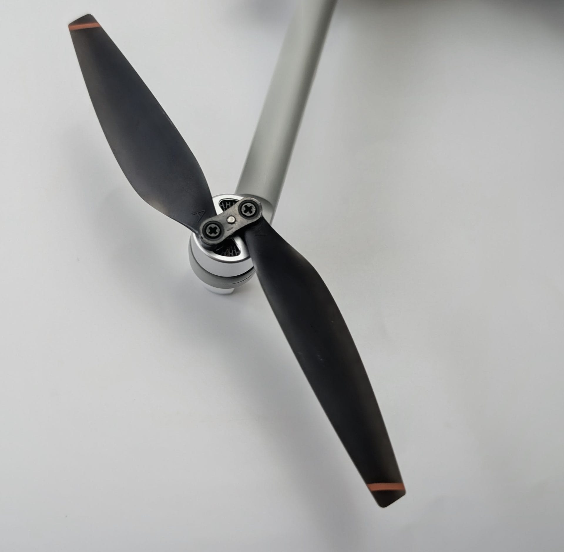 Close-up of the Ruko F11PRO 2 Plus drone’s black propeller with orange tip accents, securely mounted on the silver motor arm with visible screws and the two-blade assembly.