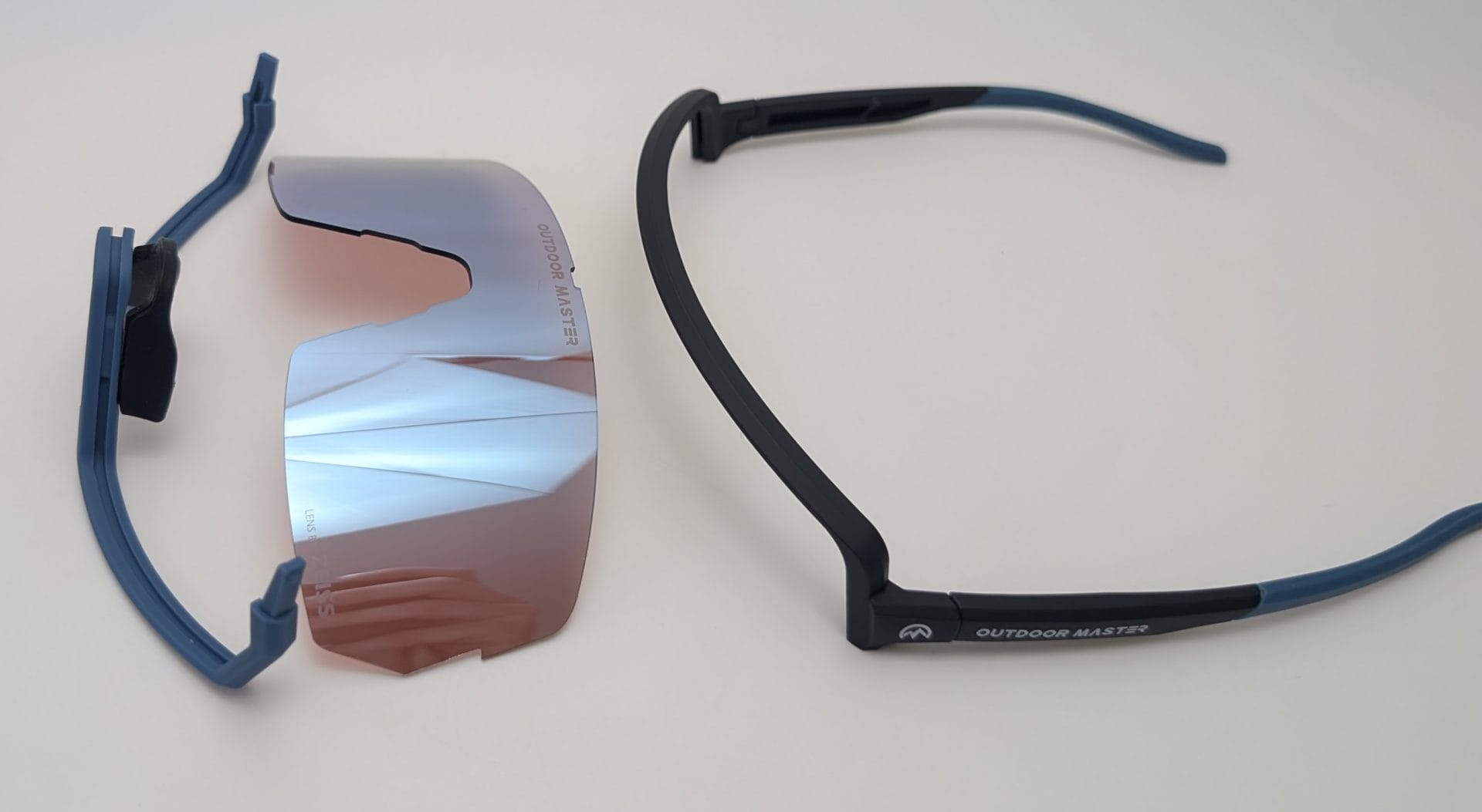 Outdoor Master Phoenix X Sports Sunglasses Disassembled Outdoor Master Phoenix X sports sunglasses showing the blue and black frame with temples on the right and the removable pink mirrored lens with nose pads on the left.