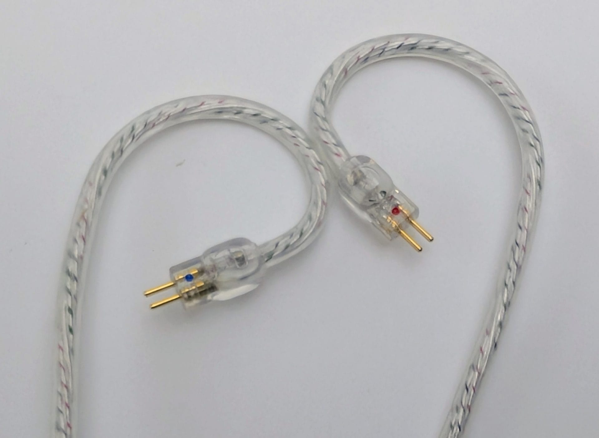 Kiwi Ears Chorus Close-up of the Kiwi Ears Chorus silver braided cable ends, showing a pair of clear plastic 2-pin connectors with gold pins (one marked with a blue dot, the other with a red dot) against a plain white background.