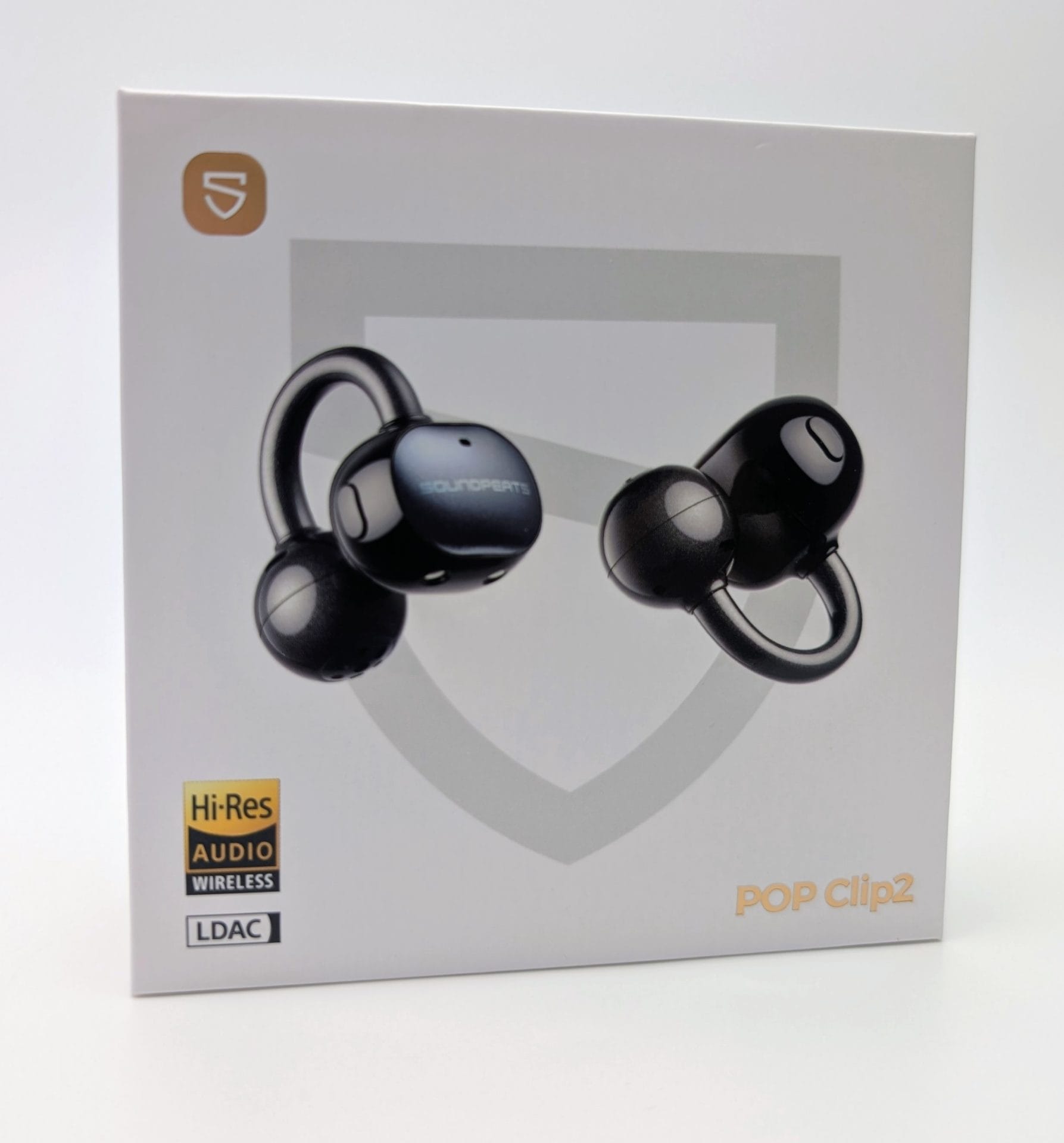SoundPEATS UU2 White retail box for SoundPEATS UU2 (also labeled POP Clip2) open-ear clip-on wireless earbuds. The front shows two glossy black earbuds with a U-shaped clip design, one facing left and one facing right. A faint shield graphic sits behind them. Badges on the box include a gold SoundPEATS “S” logo, Hi-Res Audio Wireless, and LDAC. The model name “POP Clip2” appears in gold at the bottom right.